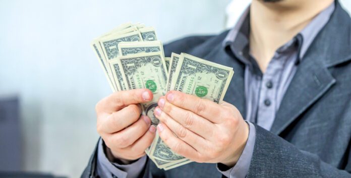 Young businessman working from his office and counting cash money A young businessman working from his office and counting cash money
