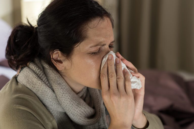 Young sick women blowing her nose.