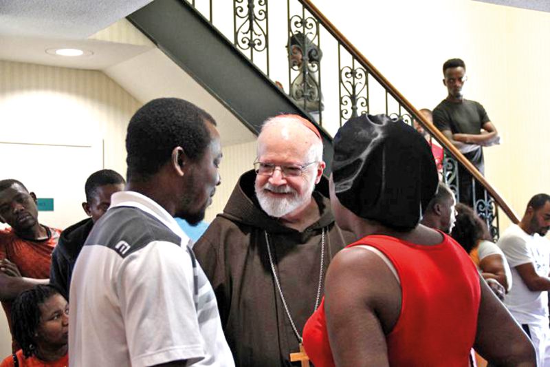 Cardinal O’Malley chats with Chivenert and Jocelyne Fenelon expectant parents who are recent arrivals to Catholic Charities Shelter.