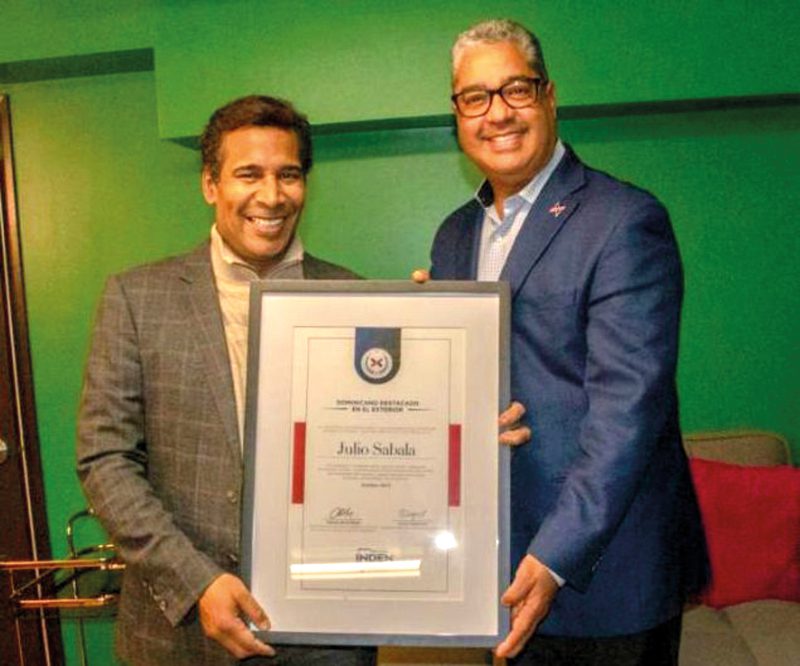 Director de INDEX-Boston entrega placa de reconocimiento a artista dominicano.