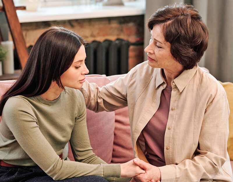 Mature woman comforting her upset daughter in home environment