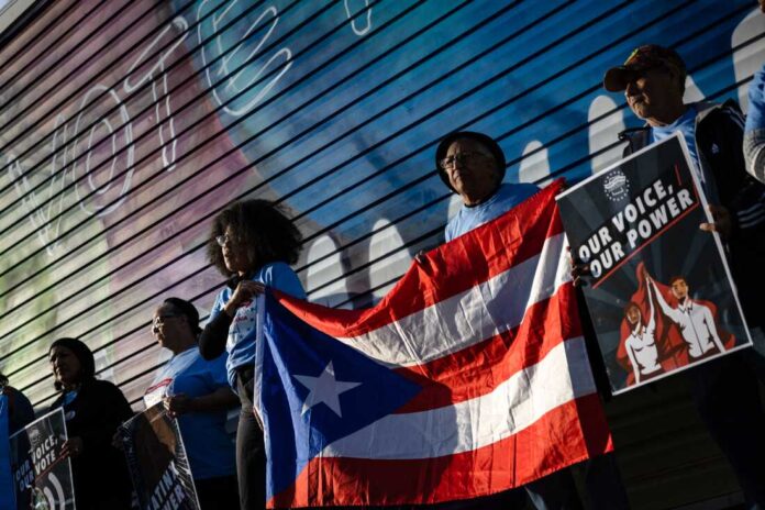 Supporters of Vice President and Democratic presidential candidate Kamala Harris hold a Puerto Rican flag during a demonstration near the PPL Center ahead of a campaign rally with former President and Republican presidential candidate Donald Trump in Allentown, Pennsylvania on October 29, 2024. (Photo by SAMUEL CORUM / AFP)