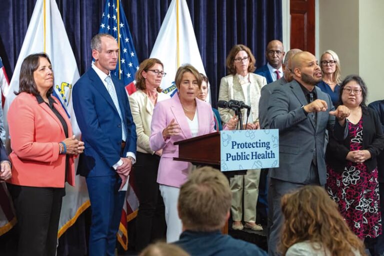 Rodeada de autoridades de salud y de la vicegobernadora Kim Driscoll, la gobernadora Maura Healey habla de la importancia de vacunarse.