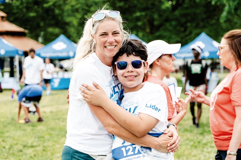 Dr. Allison Brown, Pediatrician and Medical Director of NeighborHealth’s Let’s Get Movin’ program, hugs a NeighborHealth patient before the race.