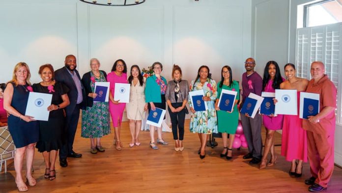 Comenzando a la izquierda: Mónica Young, Glennys Acosta, Representante Estatal Chris Worell, Melissa McWhinney, Yarlennys Villaman, Alexandra Valdez, Geneva Allison, Concejal Julia Mejia, Larissa Amezquita De Guzmán, Delia Díaz, Vladimir Mazarin, Jessica Clergeau, Kati Fernandez y Gregg Croteau.