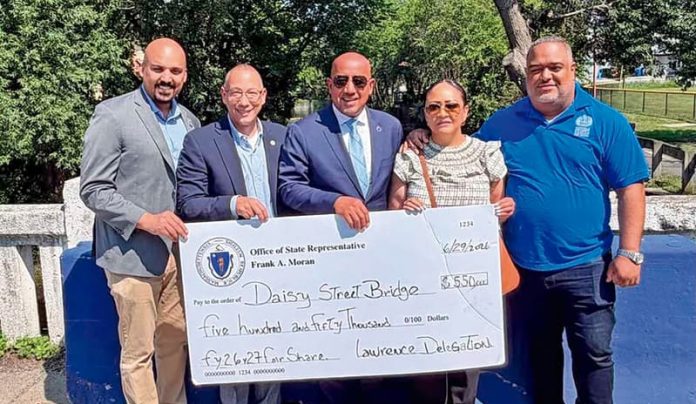 Feliz alcalde Brian de Peña recibe cheque a nombre de la ciudad de manos del Representante estatal Frank Morán rodeados del senador Pavel Payano y de los Representantes estatales, Estela Reyes y Francisco Paulino.